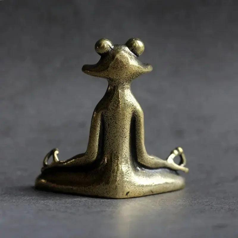 Bronze frog statue in a meditative pose on a dark background