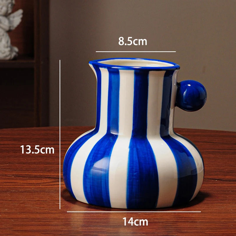 Blue and white striped ceramic vase with measurements on a wooden surface