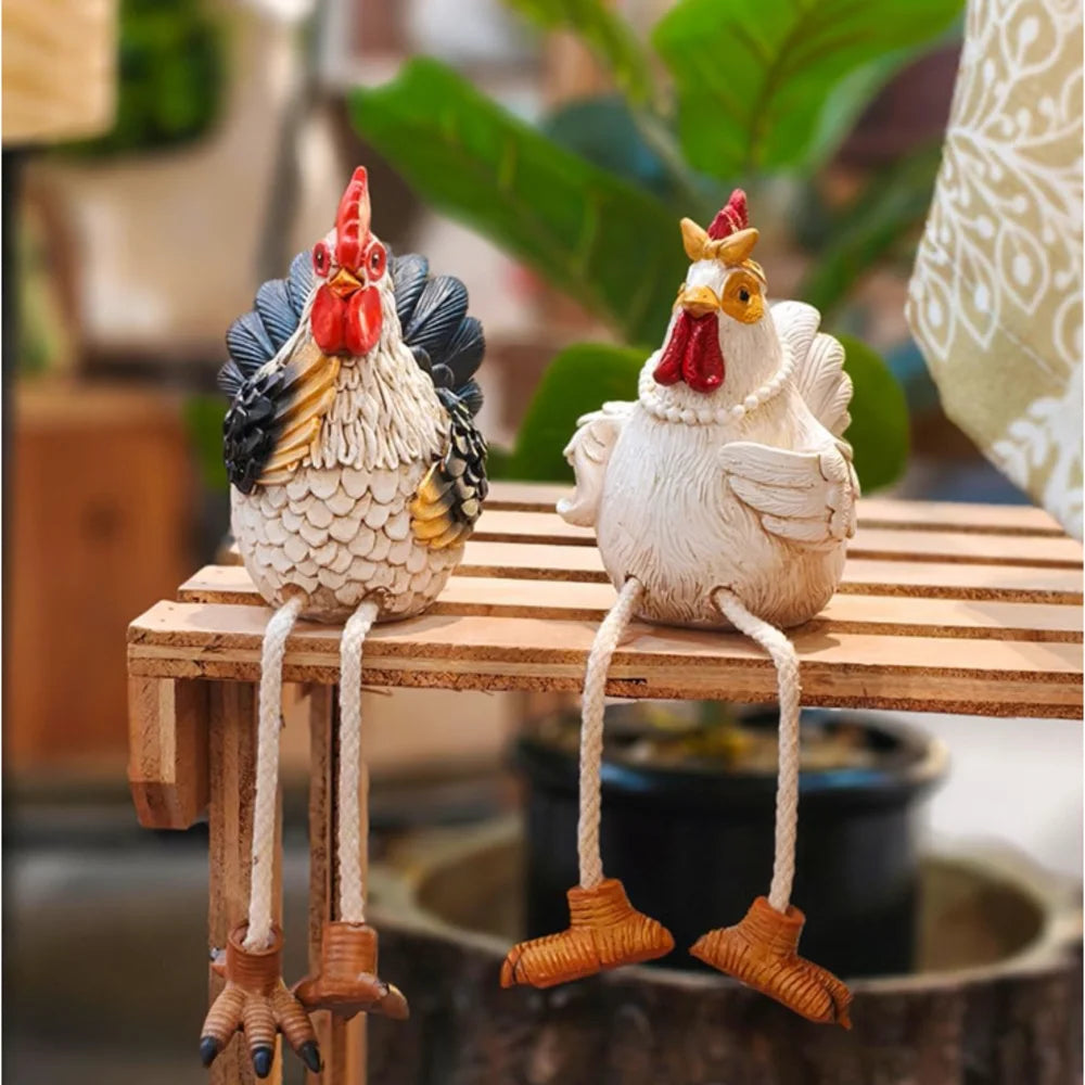 Rustic rooster and hen resin figurines with dangling legs displayed on a wooden kitchen shelf.