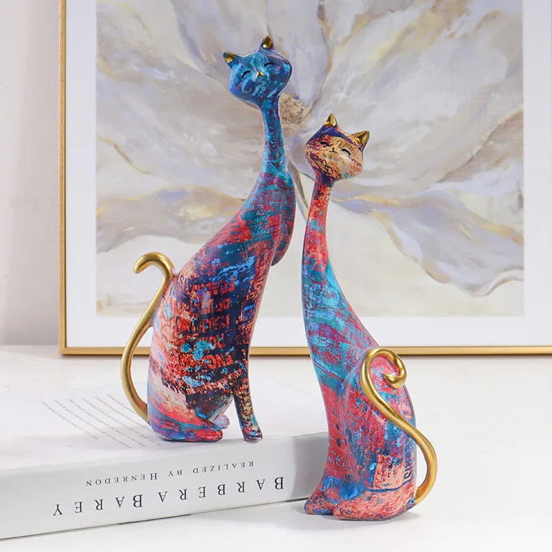 Pair of decorative resin cat sculptures with elongated modern silhouettes and artistic finishes, displayed as contemporary home decor on a tabletop.