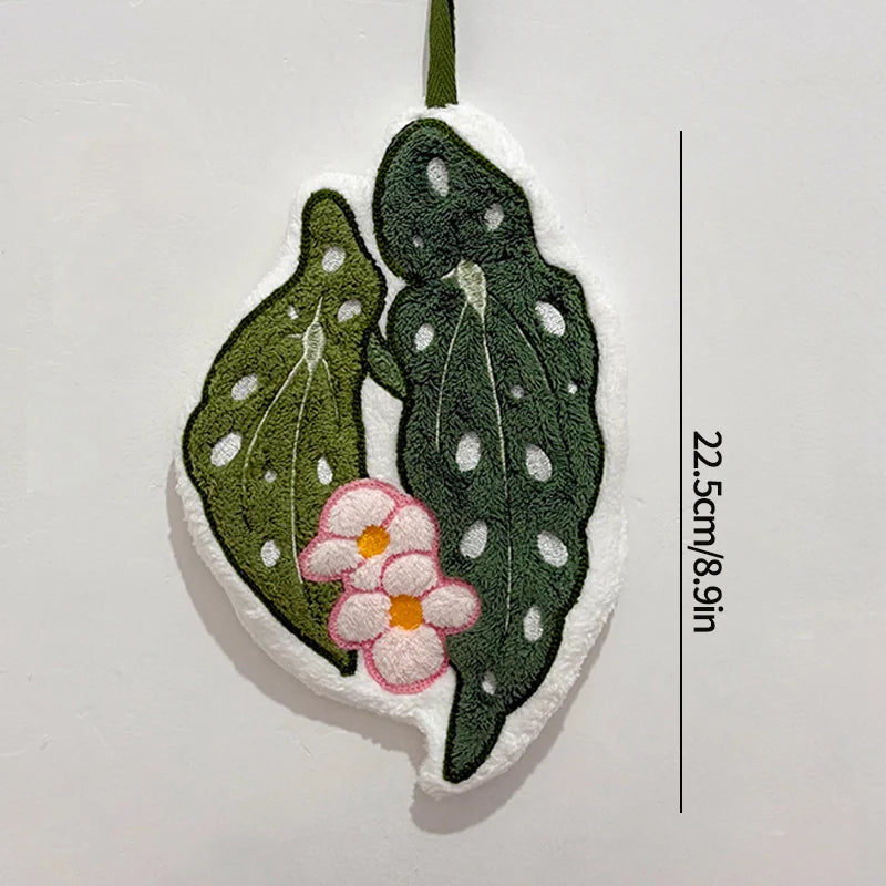 Decorative leaf-shaped towel with a flower and measurement details on a white background
