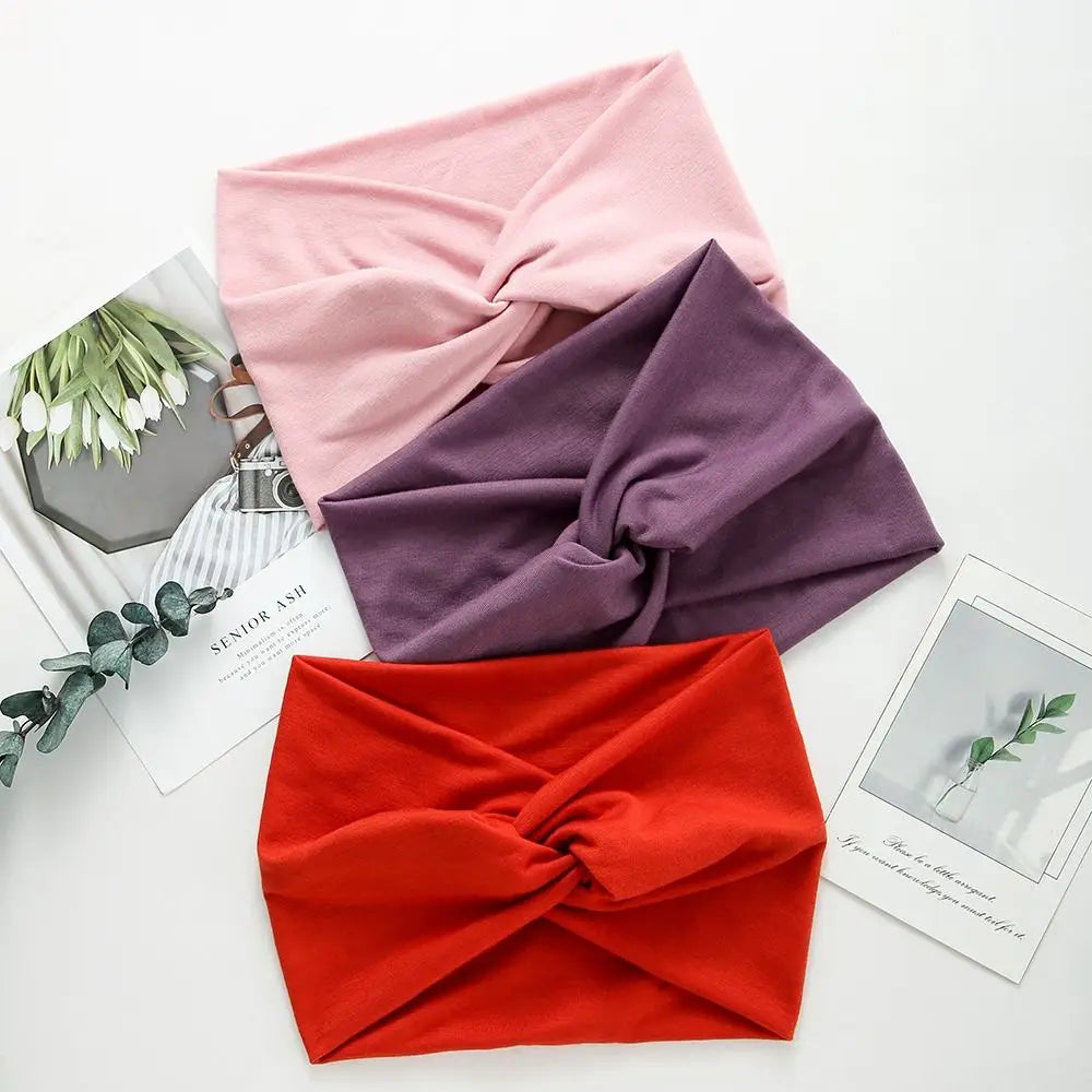 Three headbands in pink, purple, and red on a white surface with floral and magazine background.