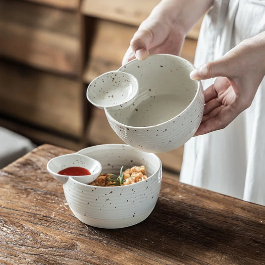 Person holding a set of ceramic bowls on a wooden table