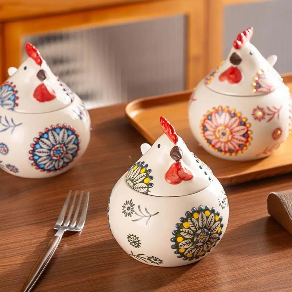 Three ceramic chicken-shaped containers with floral patterns on a wooden surface.
