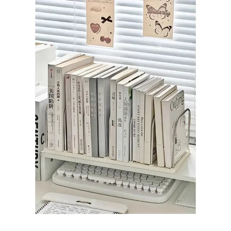 Stack of books on a desk with a keyboard and small decorative items in the background.