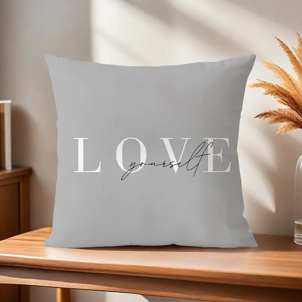 Gray pillow with 'LOVE yourself' text on a wooden surface with a neutral background