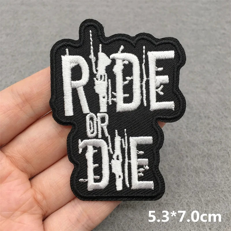 Patch with 'Ride or Die' text held by a hand on a gray background