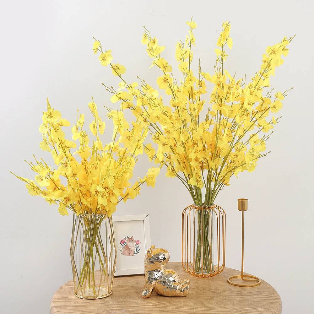 Two vases with yellow flowers on a wooden surface with decorative items.