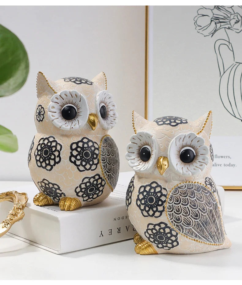 Two decorative owl figurines on a white surface with a blurred background