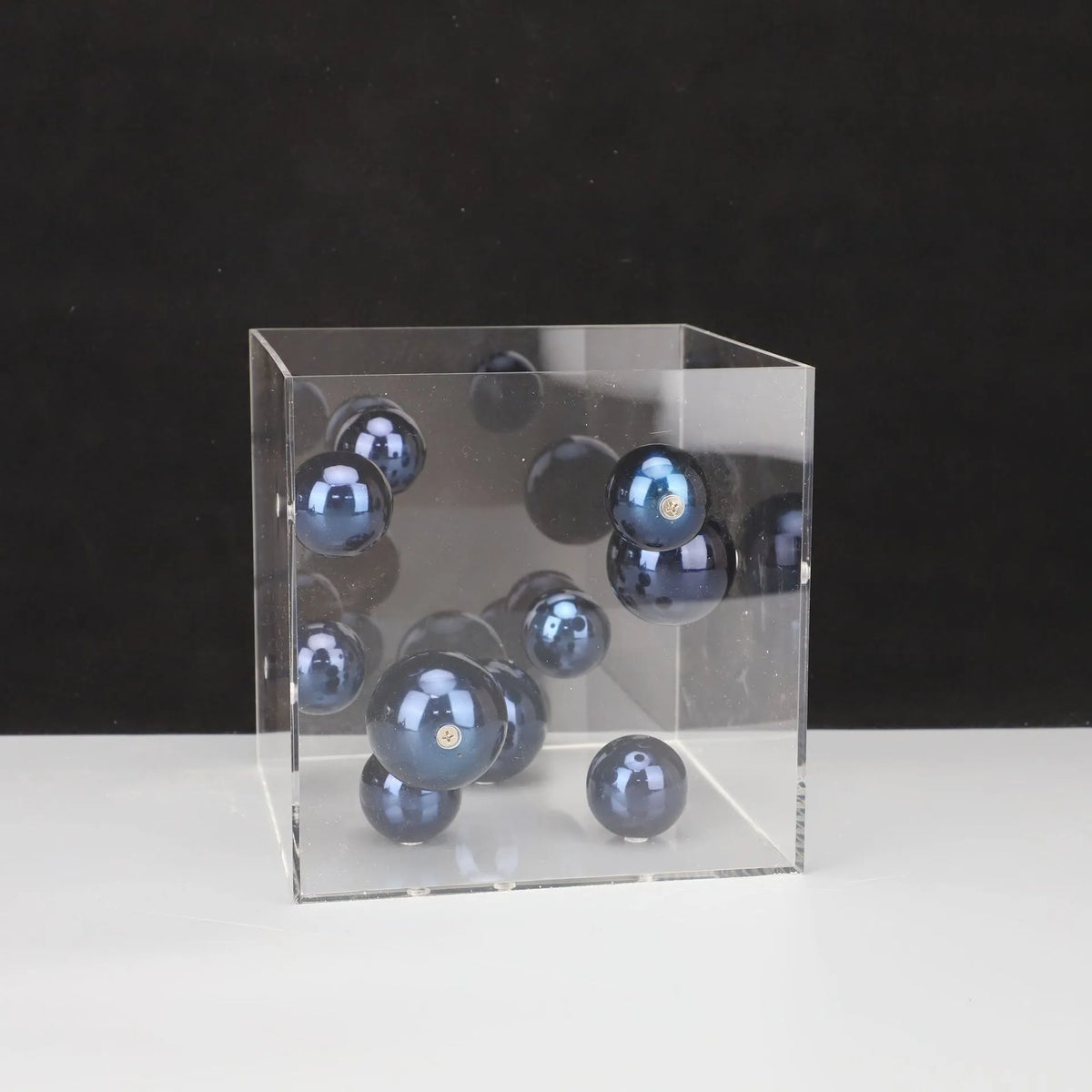 Clear cube with blue marbles on a black background