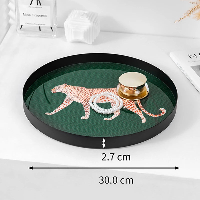 Round green tray with leopard design and jewelry, placed on a white surface.