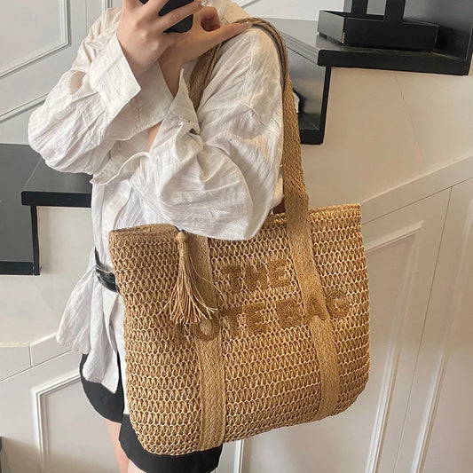 large woven straw tote bag with shoulder straps and tassel detail