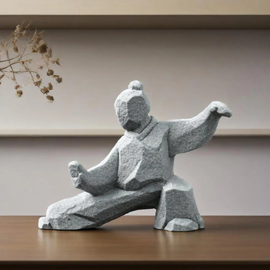 Stone sculpture of a martial artist in a dynamic pose on a wooden surface with a neutral background