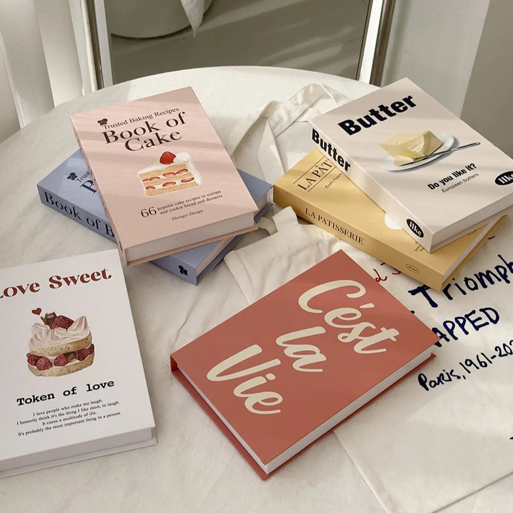 Stack of decorative books on a white surface with visible titles and images.