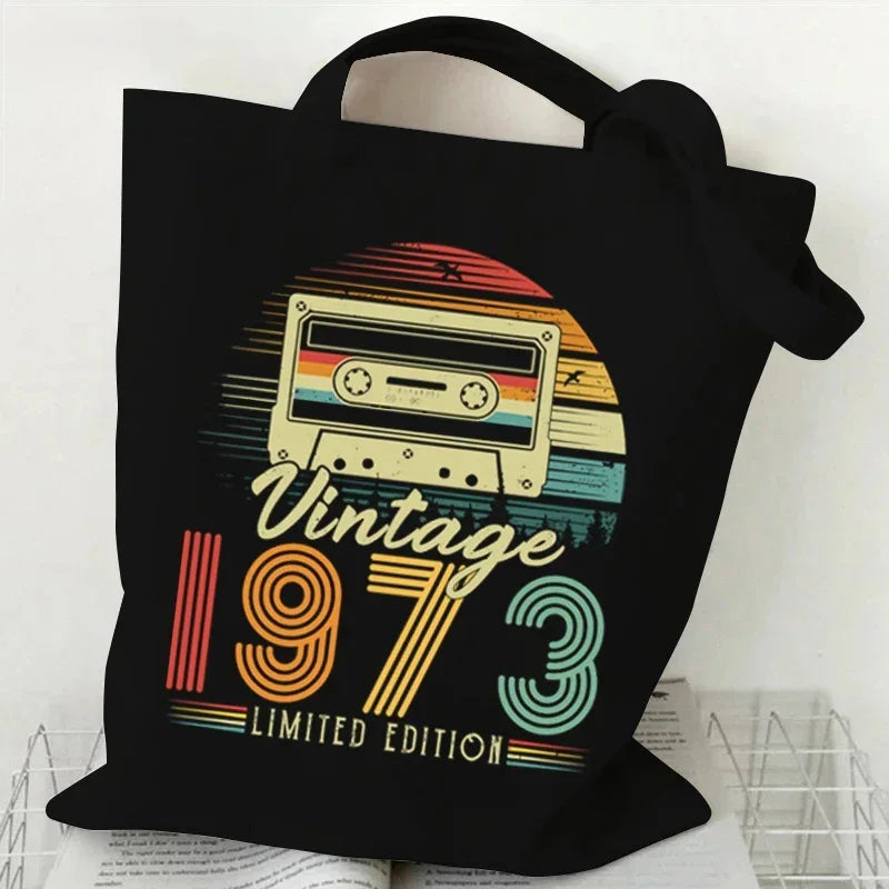 Black tote bag with a retro cassette design and 'Vintage 1973 Limited Edition' text on a white background.