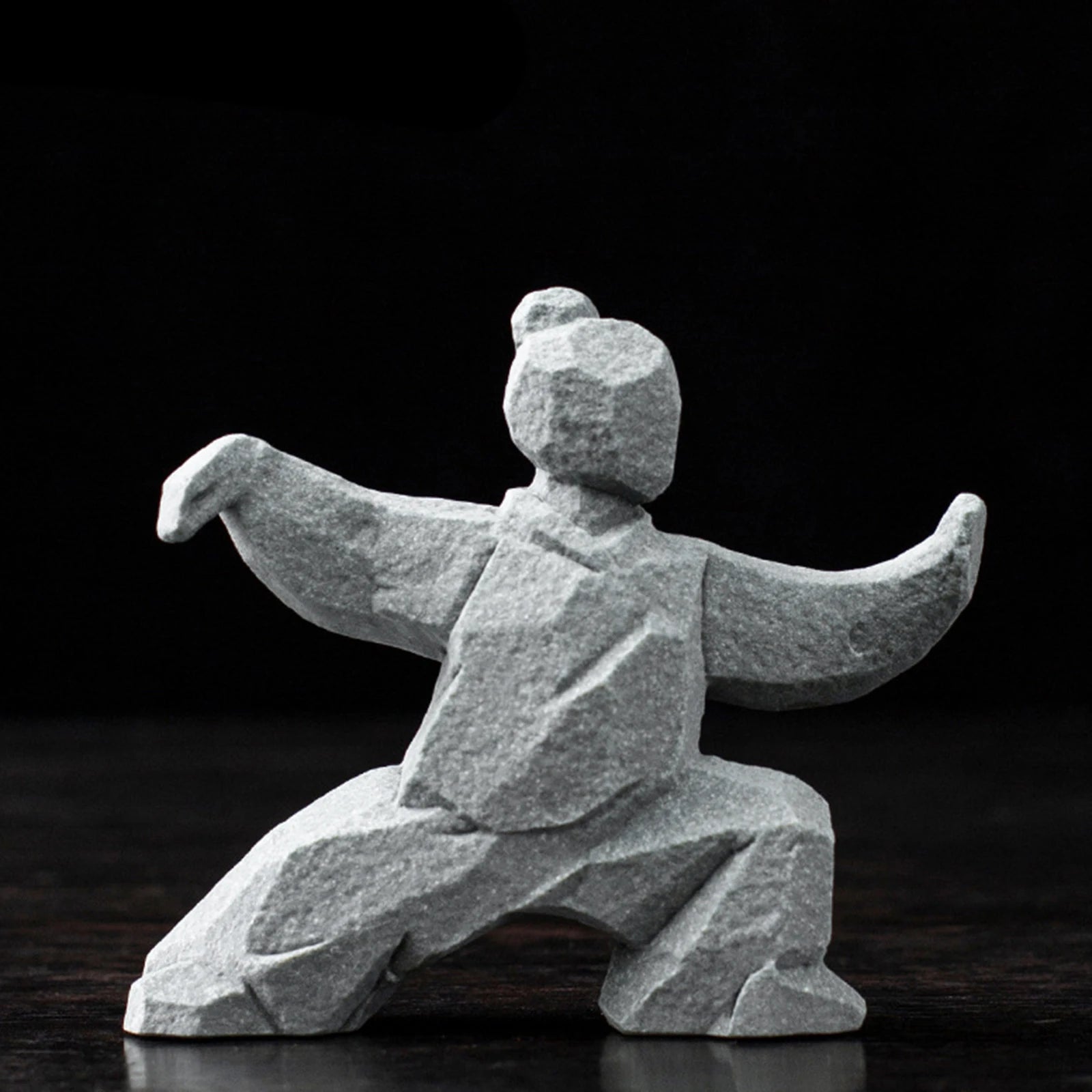 Stone sculpture of a person in a dynamic pose on a dark background