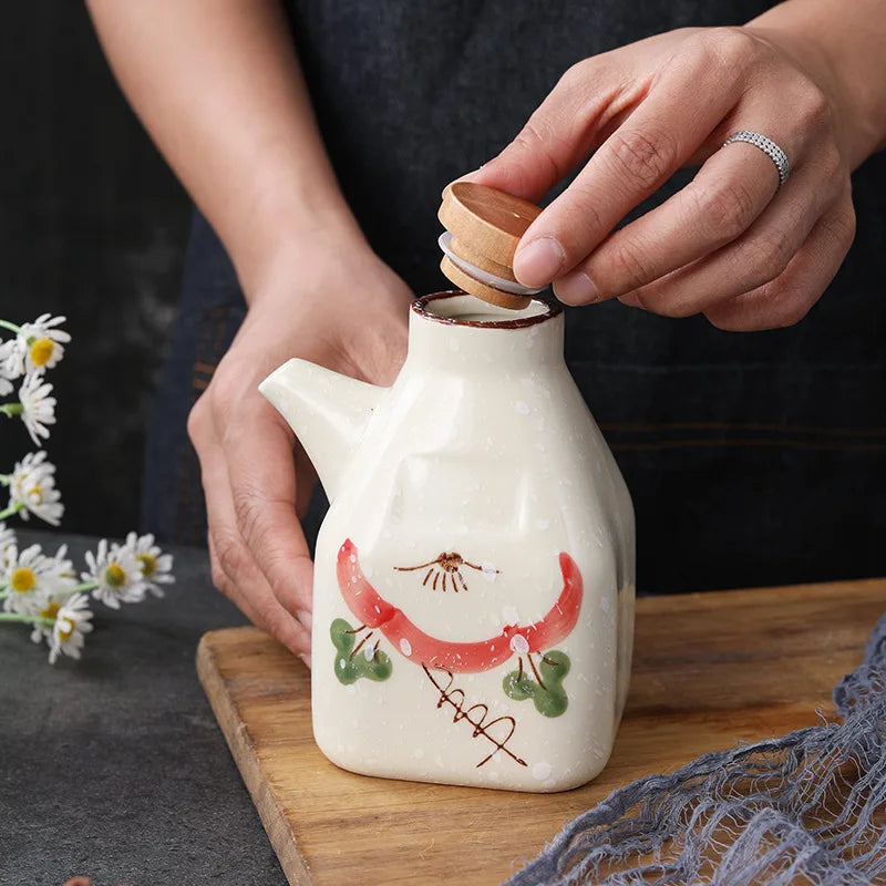 Ceramic sauce dispense with wooden lid being held by a person on a wooden surface with flowers in the background.
