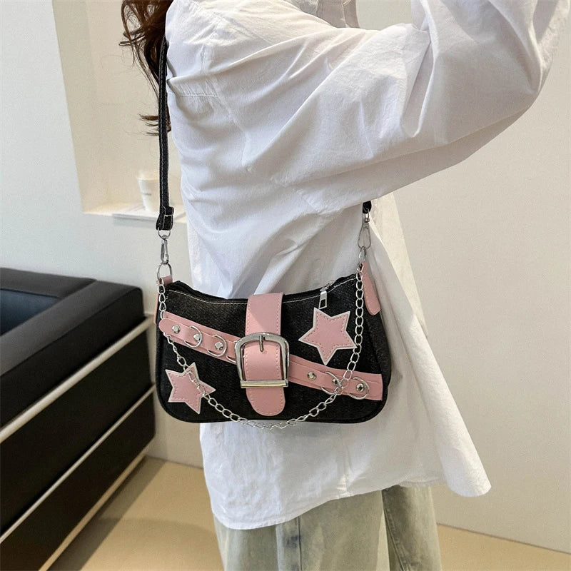 Person holding a black handbag with pink star designs and a silver buckle.