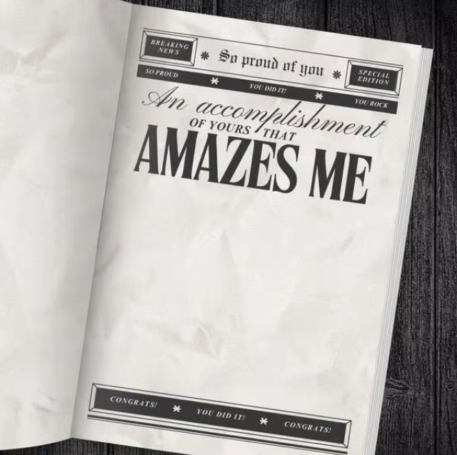 Newspaper-style card with congratulatory text on a wooden surface