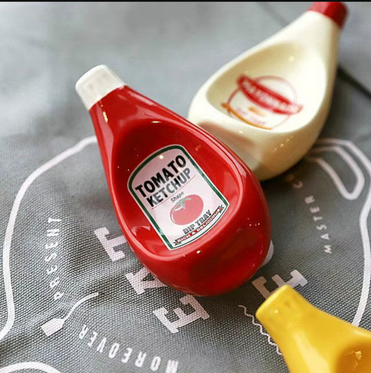 Red, cream and yellow ceramic condiment bottle dip dishes for serving sauces and dips on a dining table.