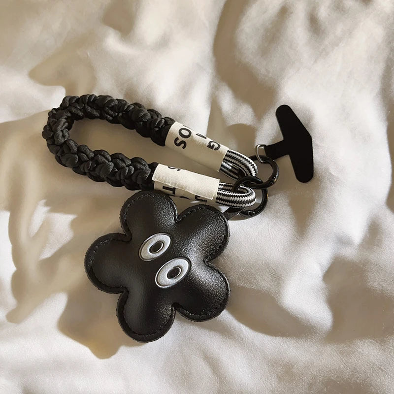 Black braided keychain with a flower-shaped key fob on a white fabric background