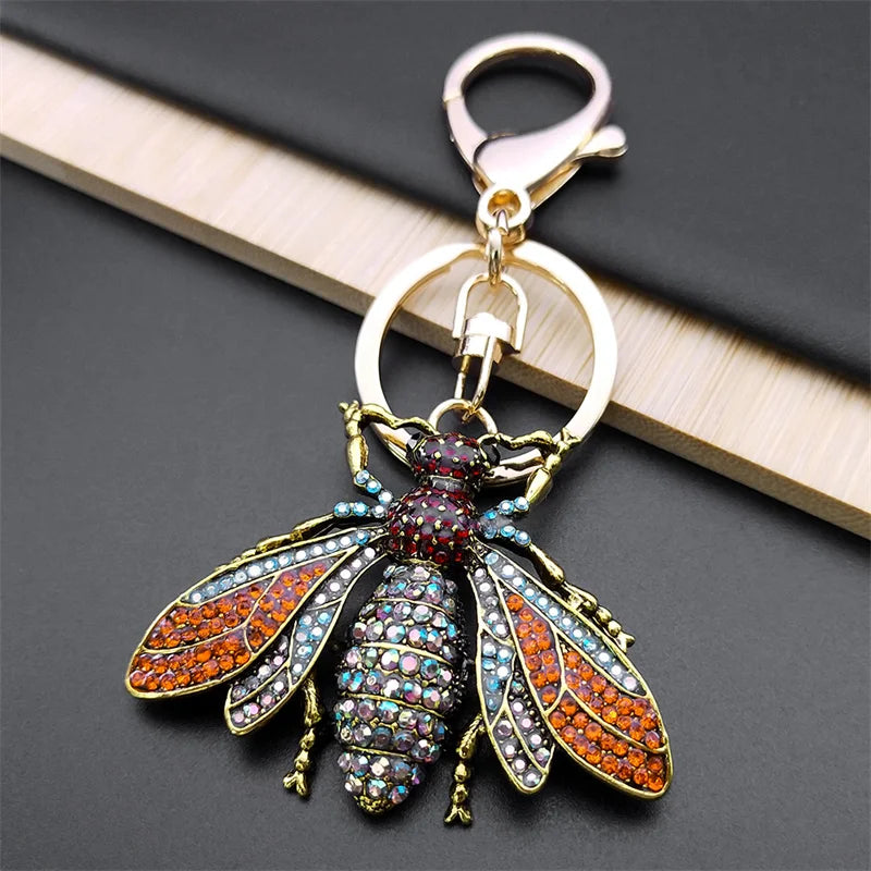 Decorative bee-shaped keychain with colorful gemstones on a dark surface