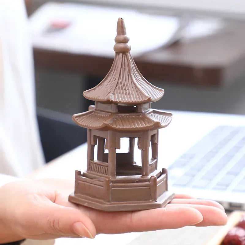 Small model of a pagoda held in a hand with a blurred background