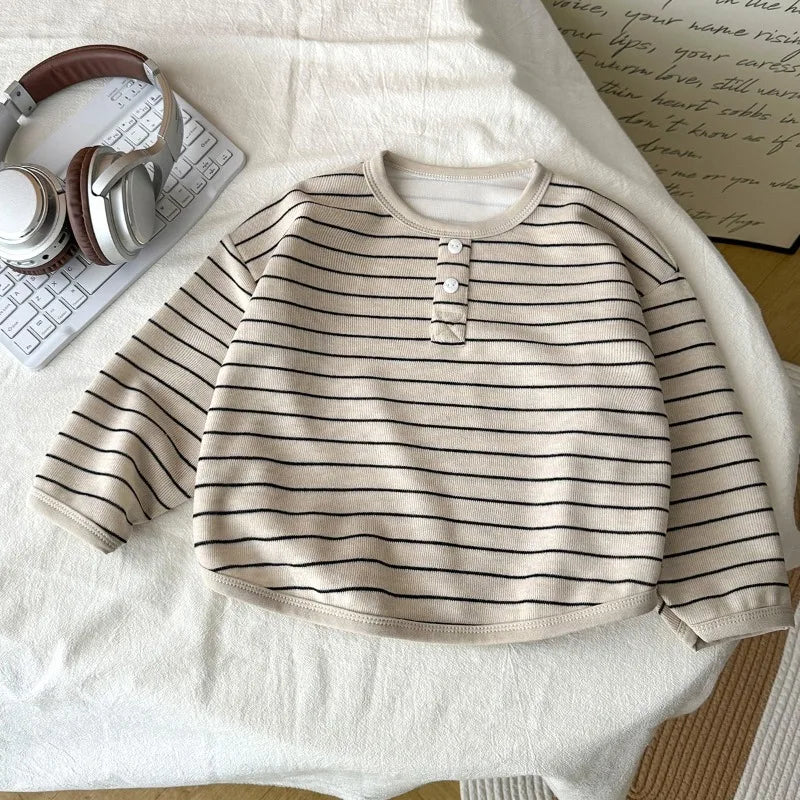 Striped sweater on a light surface with a keyboard and headphones in the background