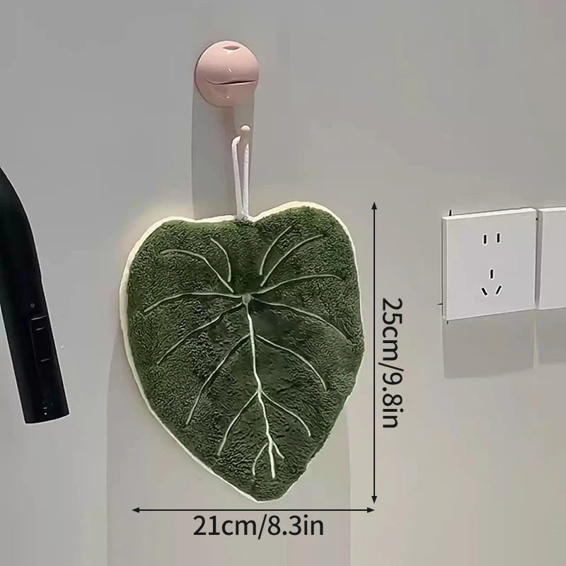 Leaf shaped hanging hand towel made from soft coral fleece fabric displayed beside a bathroom sink