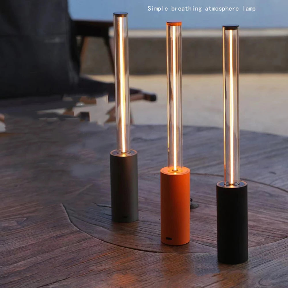 Three cylindrical lamps with different colored bases on a wooden surface.
