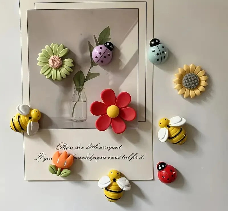 Colorful flower and insect-shaped magnets on a white surface with a framed quote.