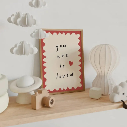 Framed picture with 'you are so loved' text on a shelf with decorative items