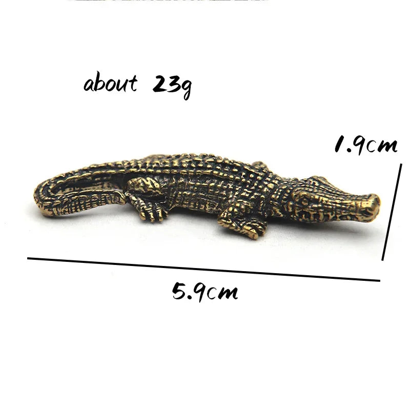 Bronze alligator figurine with measurements on a white background