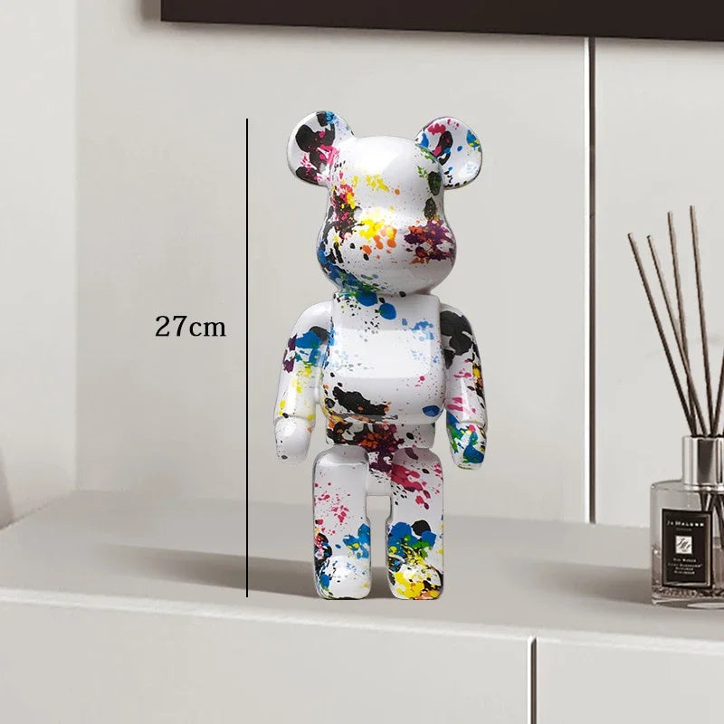 Colorful bear figurine with paint splashes on a white surface next to a diffuser.