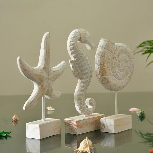 Mediterranean coastal wood sculptures featuring starfish, seahorse, and shell ornaments displayed on wooden stands in neutral interior styling