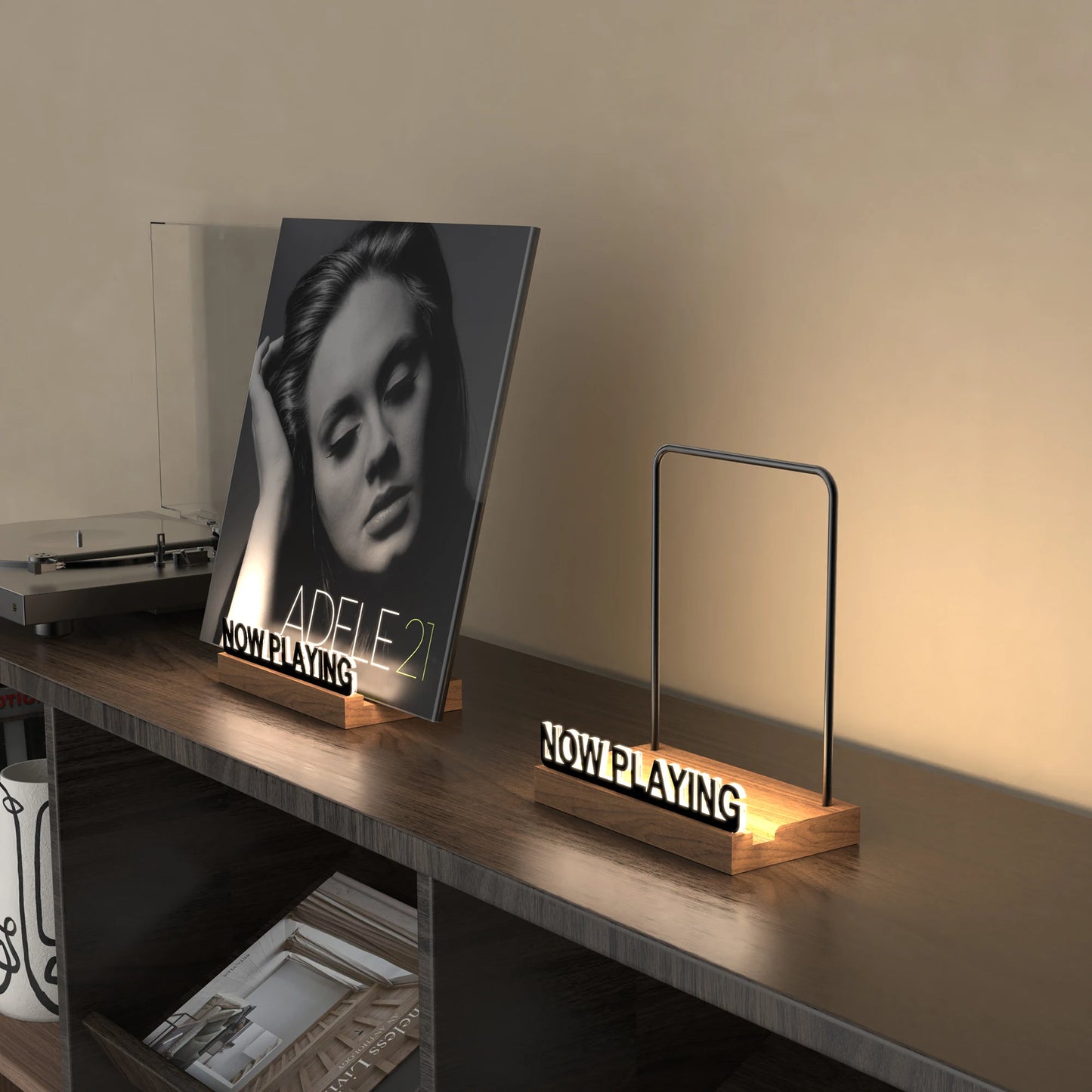 Album cover of Adele's '21' on a stand with 'Now Playing' indicator on a shelf.