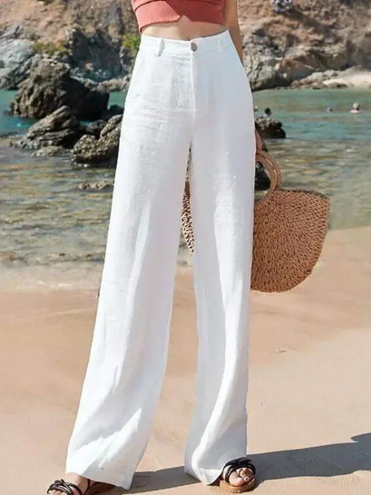 Person wearing white pants standing on  beach holding a wicker bag