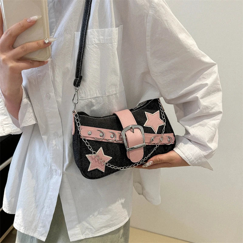 Person holding a black handbag with pink star accents and a chain detail.
