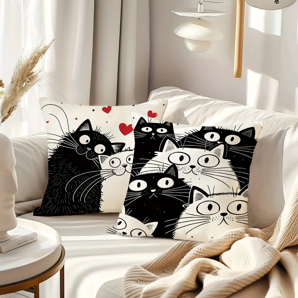 Decorative pillows with black and white cat designs on a white couch.