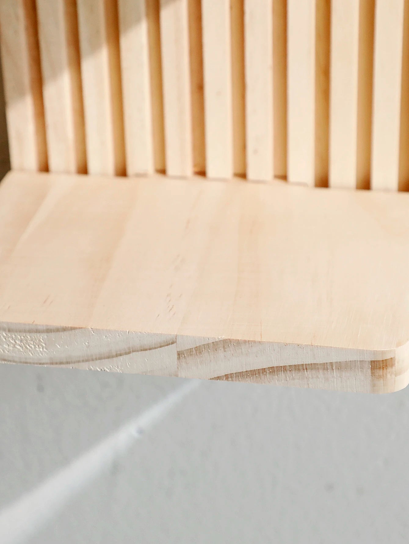 Close-up of a wooden chair with a light beige cushion on a neutral background