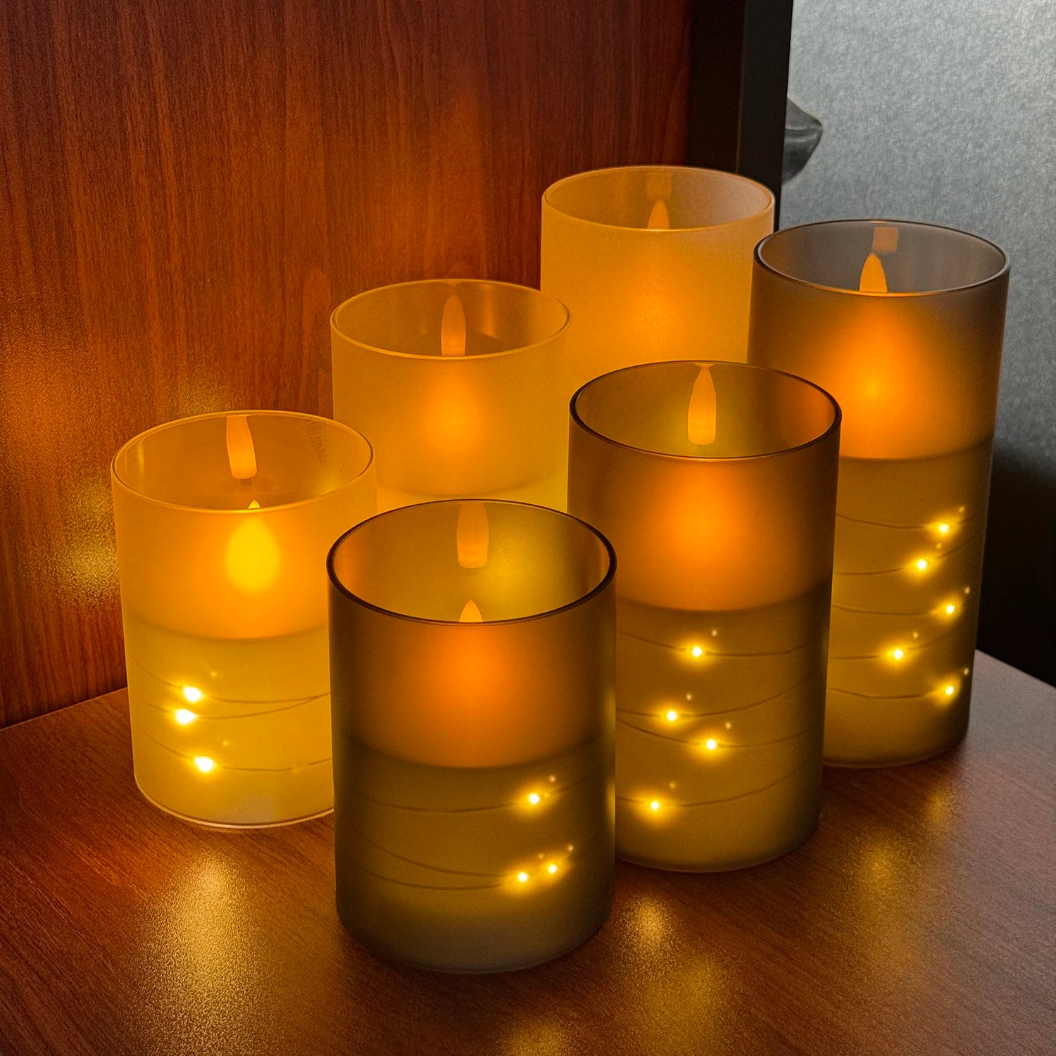 Set of glowing candles in glass holders on a wooden surface