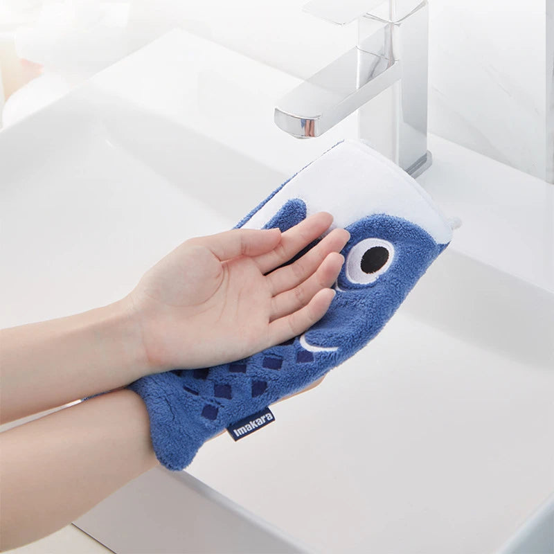Hand using a blue fish-shaped towel to dry hands in a sink.