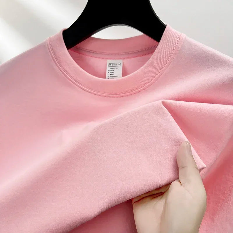 Pink sweatshirt on a hanger with a hand holding it, against a light background