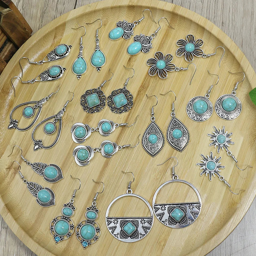 Collection of turquoise and silver earrings on a wooden tray