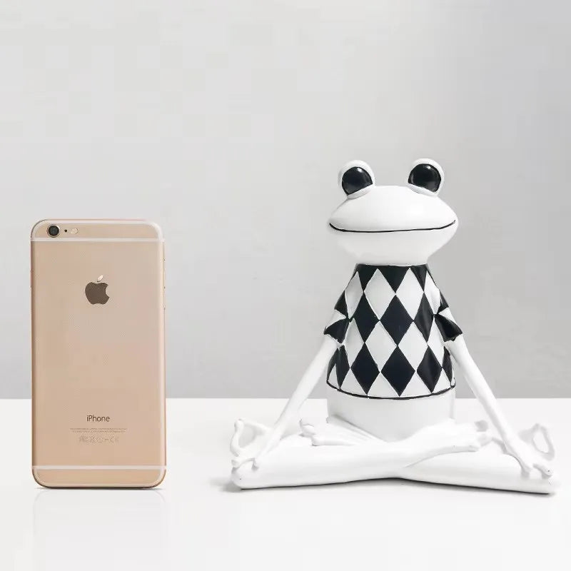 Frog-shaped figurine next to a gold iPhone on a white surface with a gray background