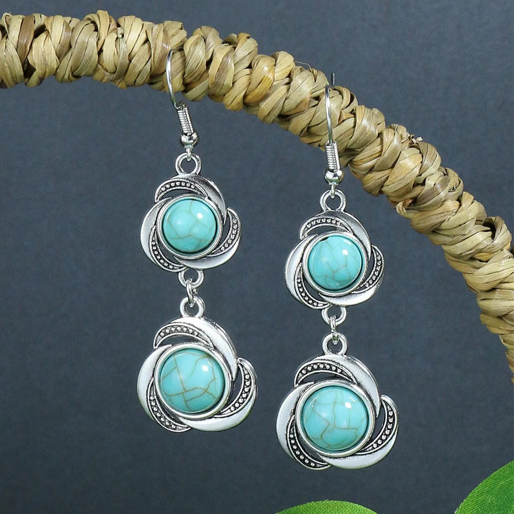 Turquoise and silver earrings on a dark background with a woven object.
