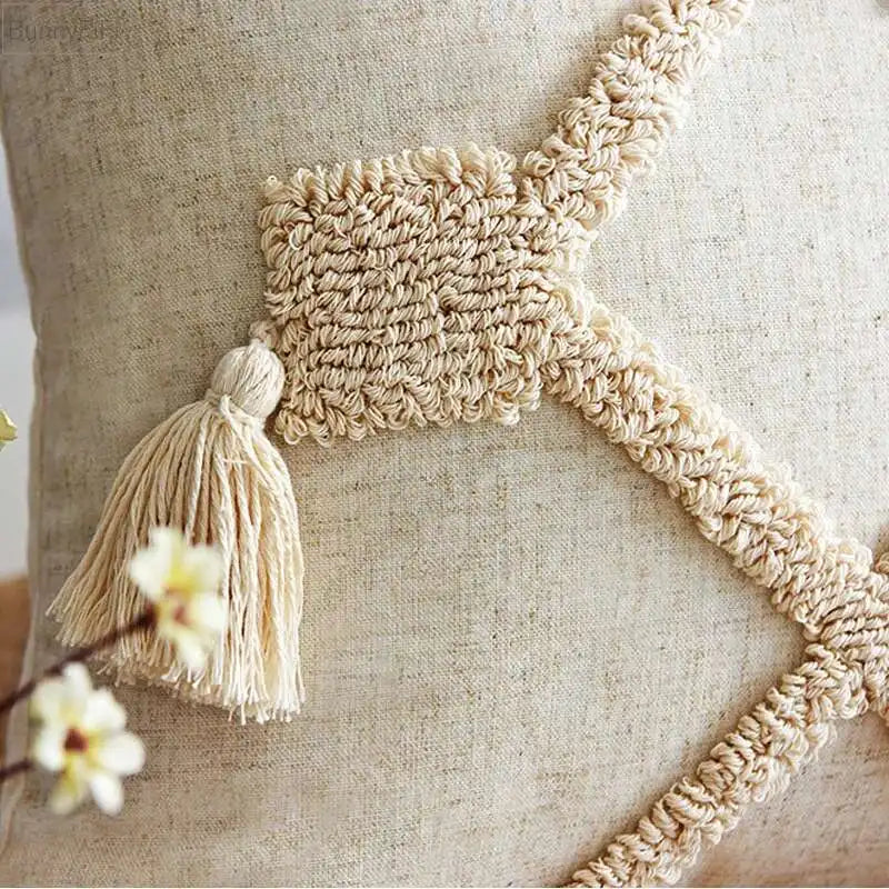 Decorative pillow with macramé trim and tassel on a neutral background