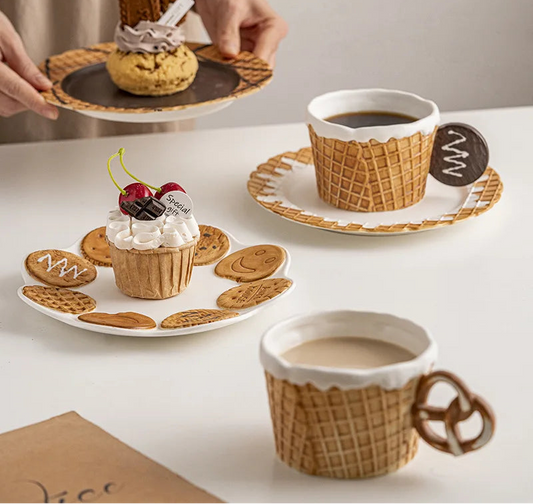 Ceramic waffle mugs and matching dessert plates displayed with coffee, cakes and biscuits for a stylish afternoon tea setting.