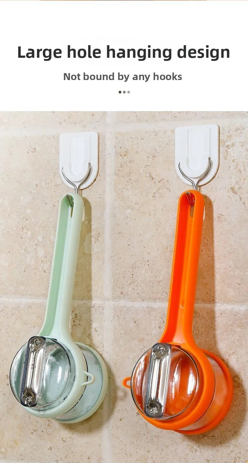 Two food slicers, one green and one orange, hanging on a large hole design hook against a beige tiled wall.