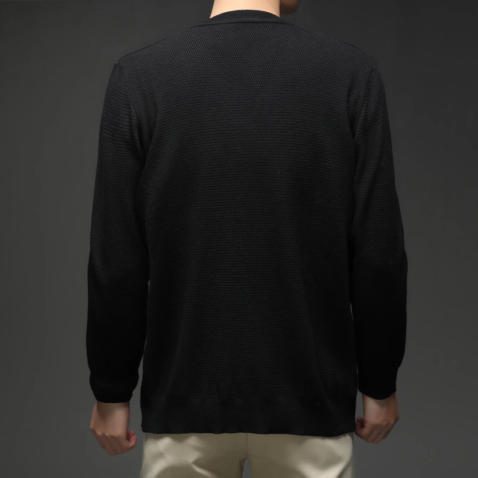 Black cardigan worn by a person on a dark background - Back View